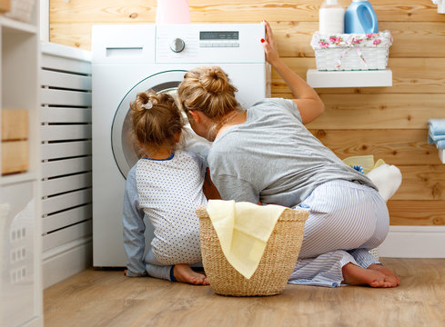Happy family mother housewife and child   in laundry with washing machine