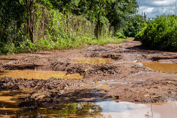 An extremely bad rural dirt road nearby Mbale after a monsoon rain shower. Local people in Uganda driving bicycles and motorbikes needs to be very skilled to drive dirt roads.