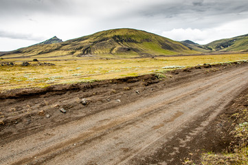 The dirt road known as F225 sinks into a landscape of hills covered with green grass, Iceland