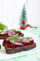 Dietary sandwiches with herring, boiled beets, red onion on rye bread on a white wooden background. Vertical view. Free space for an inscription.
