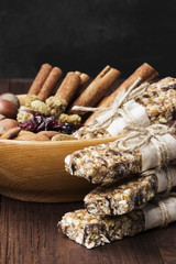 Cereal bars with nuts, berries and cinnamon on a wooden background