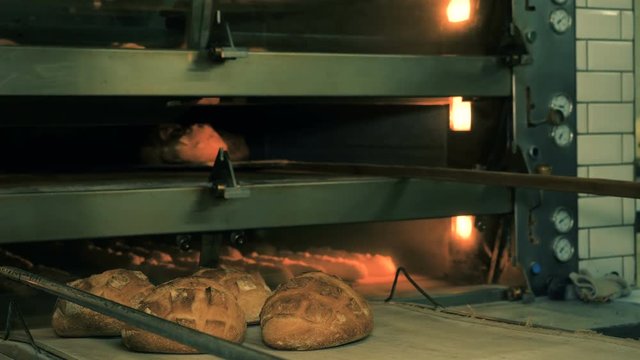 The baker takes bread out of the oven. Ready-made bakery products.