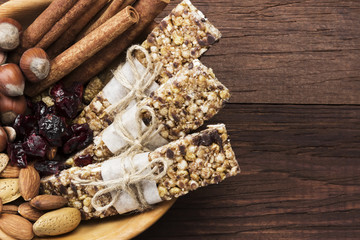 Cereal bars with nuts, berries and cinnamon on a wooden background. Top view, copy space. Food background