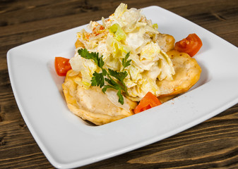 Fresh fried dumplings on bowl with salad on a wooden background.