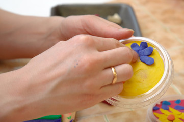 Female hands mold from a plasticine flower