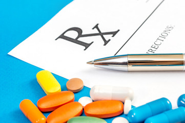Prescription form with pen and pills on a blue background. Medical concept. Medical background. Close up.