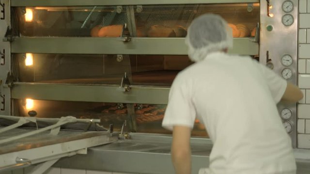 The baker takes bread out of the oven. Ready-made bakery products.