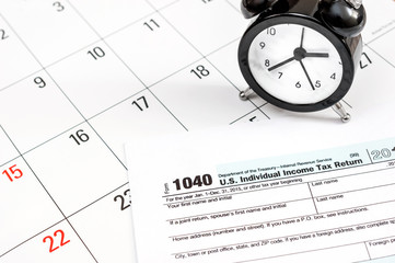 Tax form 1040 with clock on the calendar. Close up. Business concept.