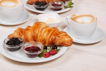 Plate with fresh croissants with jams and coffee