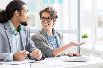 Obraz premium Confident businesswoman pointing at laptop display during presentation of her ideas to colleague