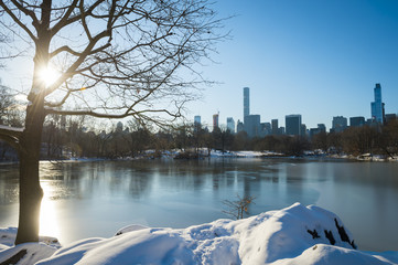 Scenic view of the Midtown Manhattan skyline reflecting in the ice of the frozen Central Park lake the morning after a winter snow storm in New York City