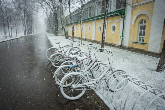 Bicycles smoothly covered with fresh snow after weather phenomena - snowfall in late April near Moscow