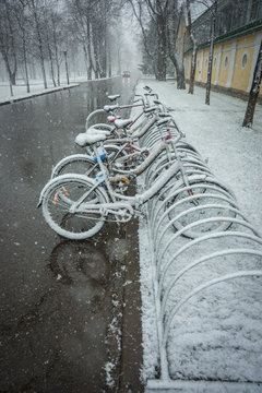 Bicycles smoothly covered with fresh snow after weather phenomena - snowfall in late April near Moscow