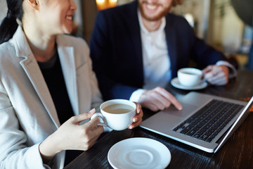 Mobile colleagues discussing online video or information while having tea break