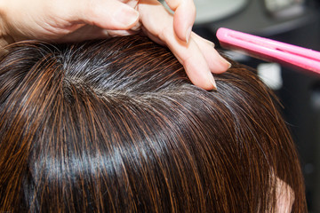 Close-up on gray hair roots of woman against dark hair