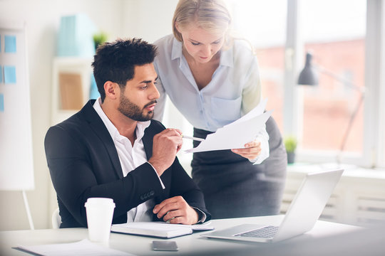 Confident boss pointing at financial paper in his secretary hand in office