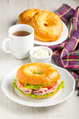 Bagel sandwich with ham, cheese, tomato, green salad lettuce, tea, tatsy breakfast