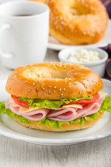 Bagel sandwich with ham, cheese, tomato, green salad lettuce, tea, tatsy breakfast