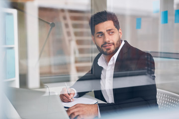 Inspired businessman looking through office window while brainstorming by workplace