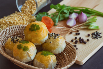 Chinese pastry or moon cake on wood basket with some ingredient on black granite table in top view, close up. Homemade bakery concept.