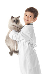 Cute little boy in doctor uniform playing with fluffy cat on white background