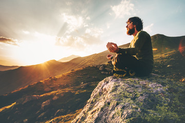 Man meditating yoga lotus pose at sunset mountains Travel Lifestyle relaxation emotional concept summer vacations outdoor harmony with nature - obrazy, fototapety, plakaty