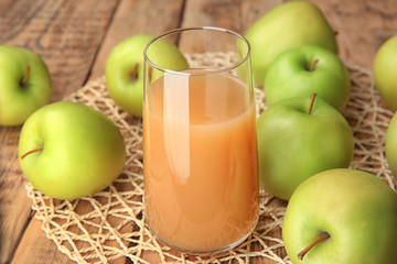 Glass with fresh apple juice on wooden table