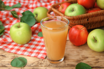 Glass with fresh apple juice on wooden table