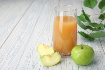 Glass with fresh apple juice on wooden table
