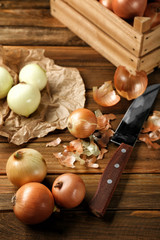 Raw onions and knife on wooden background