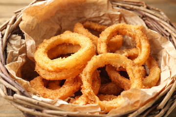 Wicker basket with fried breaded onion rings, closeup