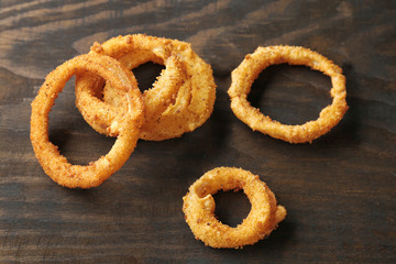 Fried breaded onion rings on wooden background