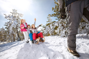 Fototapeta na wymiar Children with hand up sitting on sledge together