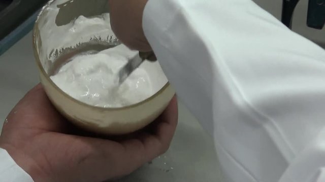 Close-up of a dental technician who is mixing plaster in a container to make dental molds. Dental prosthetic laboratory.