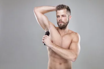 Foto op Plexiglas Handsome bearded man with a trimmer shaving off body hair © and.one