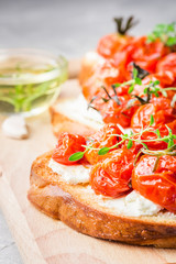 Roasted cherry tomatoes and goat cheese bruschetta. Selective focus, close up.