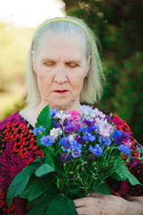 Elderly grandmother with a bouquet of flowers in the park