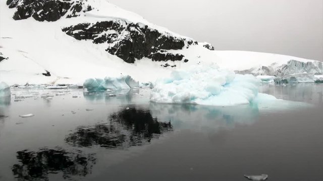 Ice floe and iceberg in ocean of Antarctica. Glacier on background of snow mountains.Travel in calm cold polar north. Scenic blue water. Global warming. Unique nature of desert . Wilderness area.