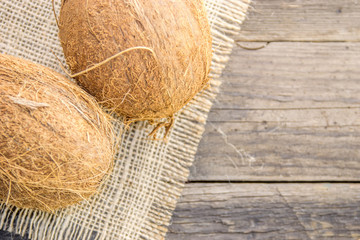 Coconut nuts, ripe, on a rustic jute base on a wooden table
