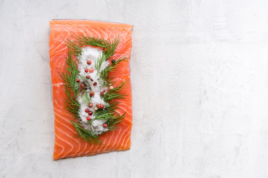 Homemade salmon steak with dill and salt on a white concrete background with copy space. Top view.