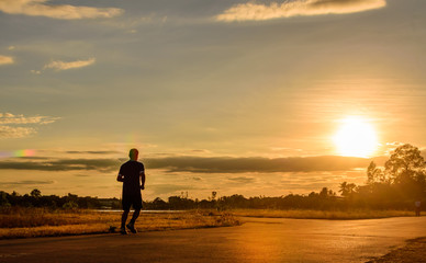 Silhouette of a man  jogging for exercise in park at sunset,