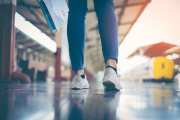 A Walking young girl tourist on side railway holding smartphone with backpack going to travel scenery town tour around at train station platform for take the rest, happy and life experience having fun