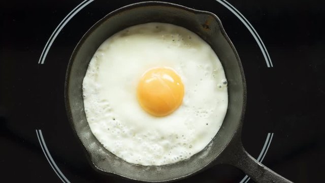 Fried egg on a pig-iron frying pan preparation process time lapse.