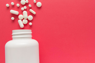 Capsules spilling out of white bottle. Red background. Line, way course concept.