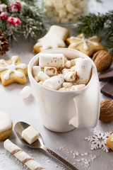 A cup of hot chocolate with marshmallows and gingerbread on a Christmas table.