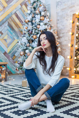 Christmas. Beautiful smiling girl. is sitting over christmas tree lights background. happy new year.
