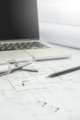 black pencil and computer laptop on architectural drawing paper for construction