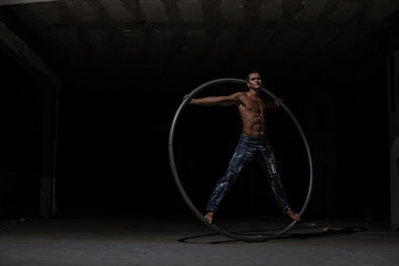 Fototapeta na wymiar Muscular circus artist in a Cyr Wheel (Roy Cyr) on a black background
