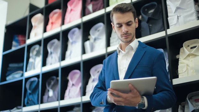 Man working on tablet computer at shirt store