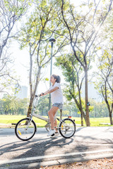 Naklejka premium Portrait of happy beautiful smiling young woman on bicycle in the park